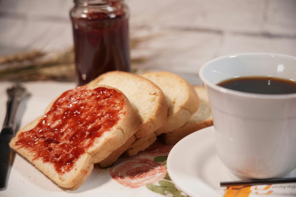 Sliced toast with strawberry jam and a cup of coffee, perfect for a cozy breakfast moment.